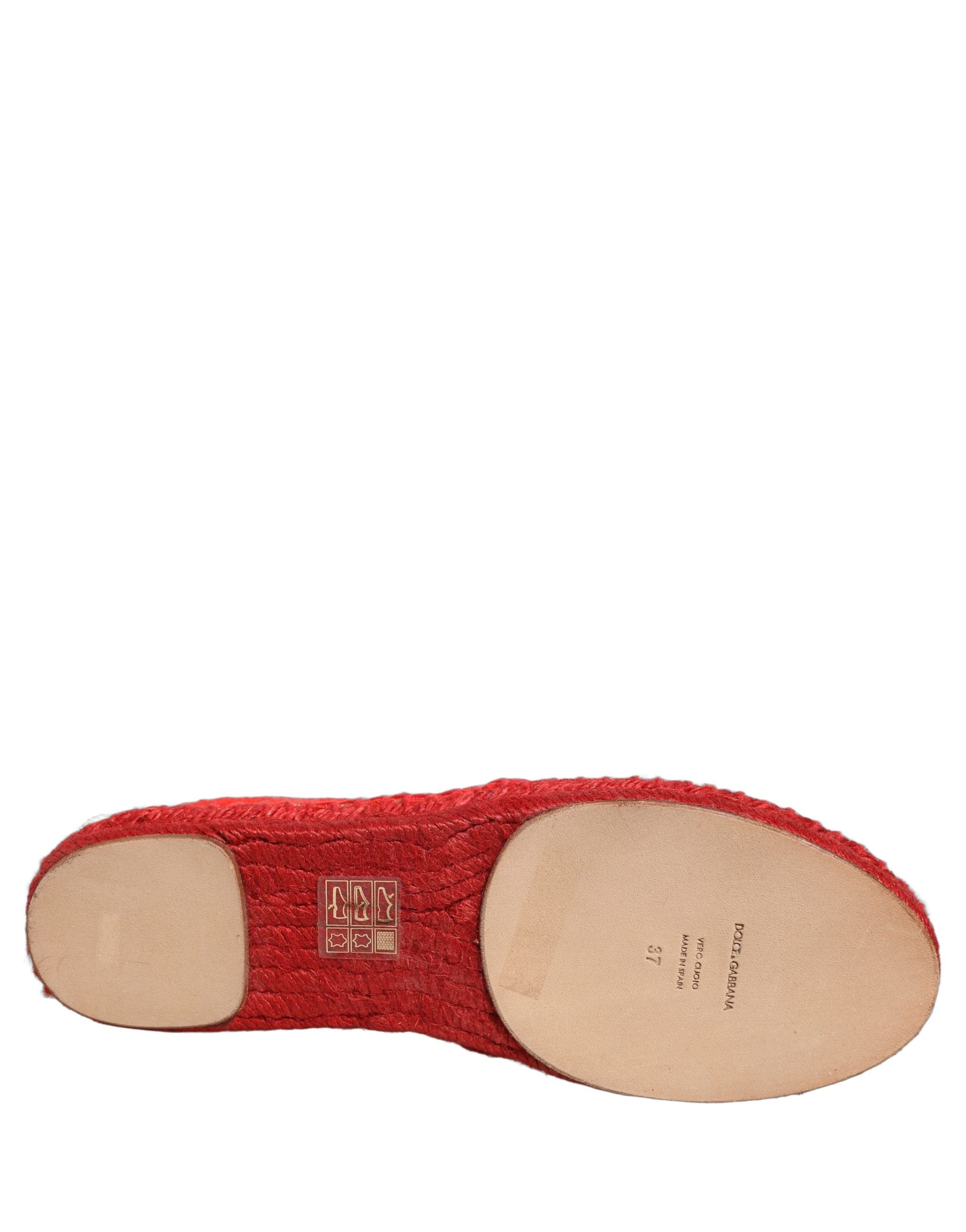 Female model wearing vibrant red floral lace espadrille slip-on shoes with a sheer lace overlay, rope-stitched espadrille sole, and bold red colourway, captured mid-step in a casual lifestyle pose showcasing the shoe's elegant profile and delicate lace detailing.