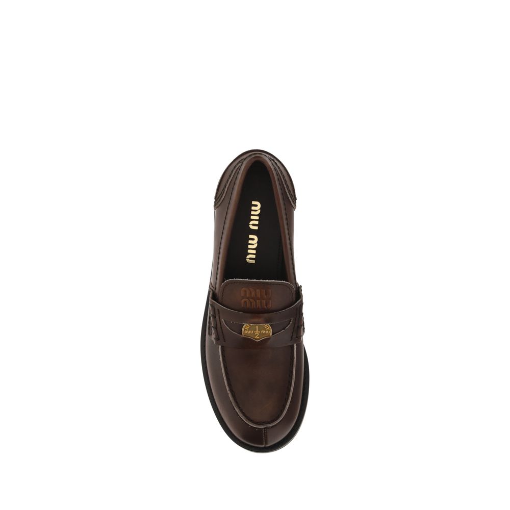 Brown loafer shoe with 'miu miu' branding on a white background