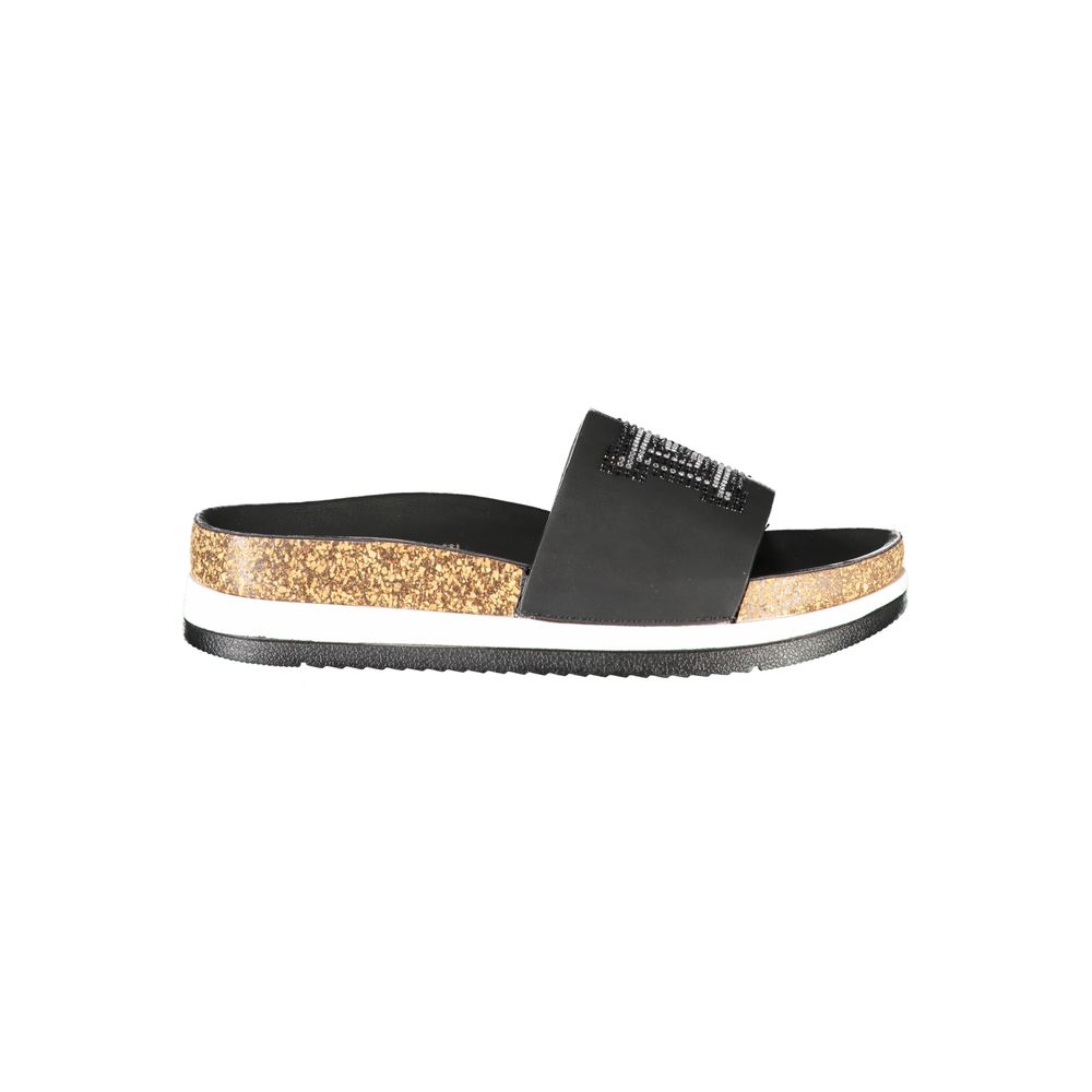 Female model wearing Laura Biagiotti nero black polyurethane women's slipper with a sleek black upper, effortless slip-on silhouette, and refined Italian craftsmanship, captured mid-step in a casual lifestyle pose showcasing the slipper's understated sophistication and relaxed everyday luxury.