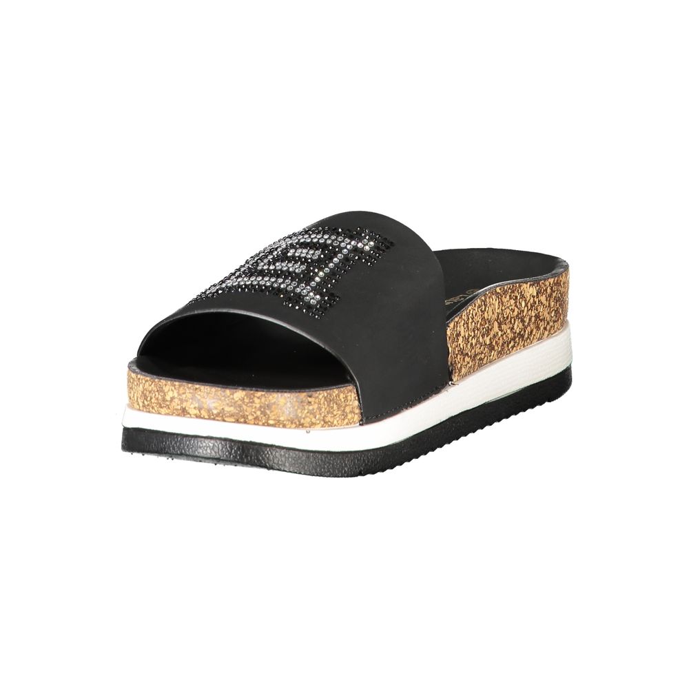 Female model wearing Laura Biagiotti nero black polyurethane women's slipper with a sleek black upper, effortless slip-on silhouette, and refined Italian craftsmanship, captured mid-step in a casual lifestyle pose showcasing the slipper's understated sophistication and relaxed everyday luxury.