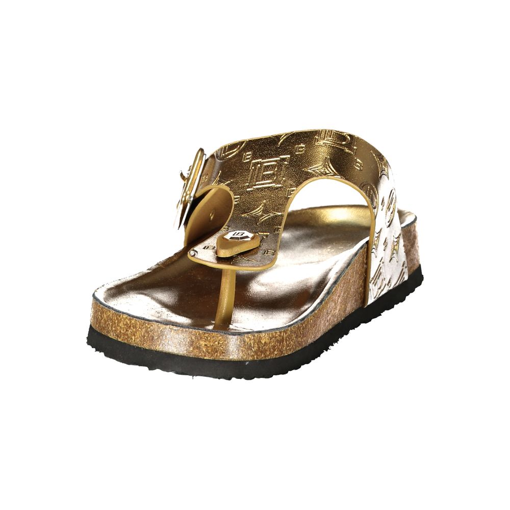 Female model wearing Norway 1963 gold metallic embossed leather thong sandal with a richly textured gold upper, adjustable side buckle strap, natural cork footbed, and black rubber outsole, captured mid-step in a casual lifestyle pose showcasing the sandal's opulent golden glamour and effortless summer luxury.