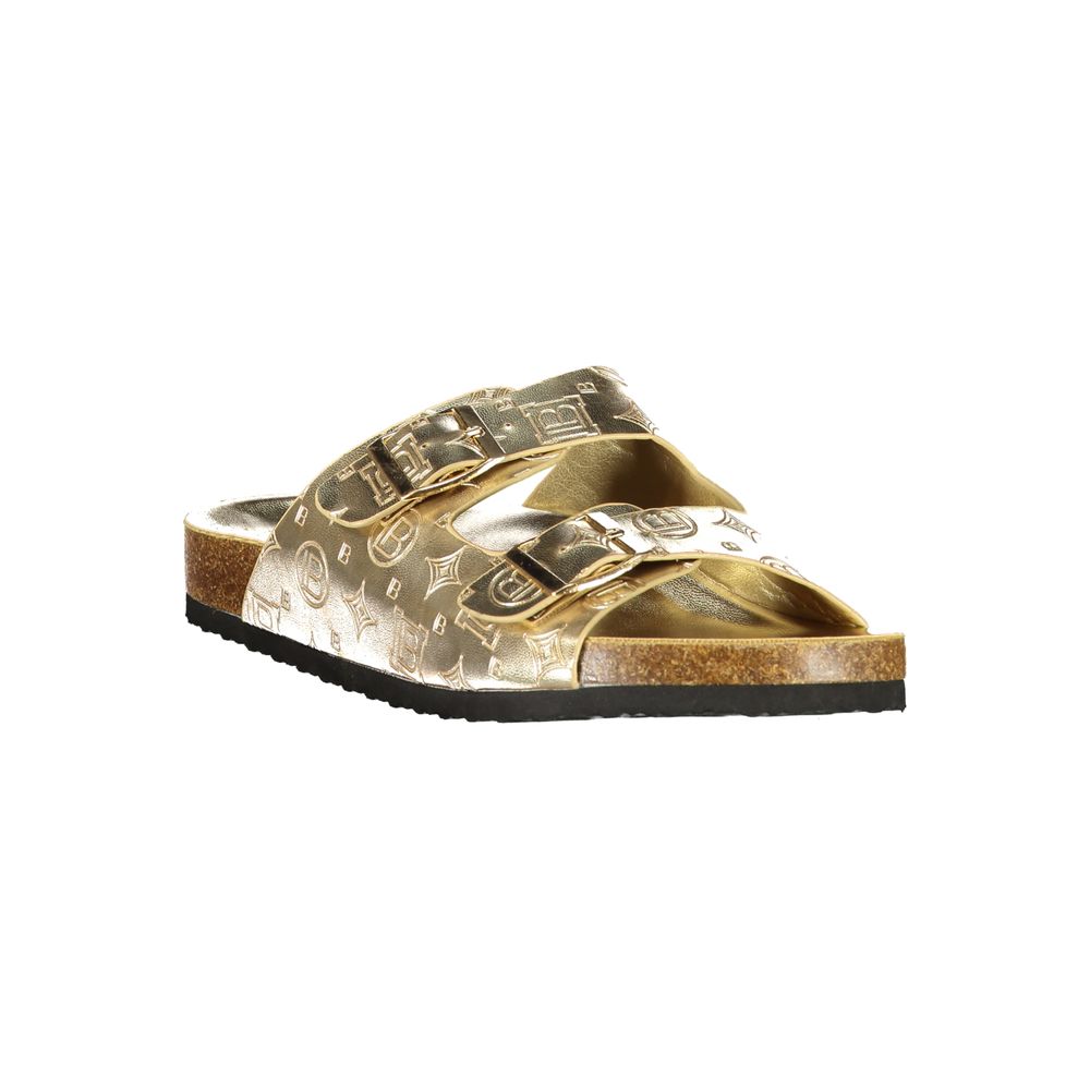 Female model wearing Laura Biagiotti gold polyethylene flat sandals with lustrous gold-tone straps, lightweight construction, and refined Italian detailing, captured mid-step in a casual lifestyle pose showcasing the sandal's glamorous summer elegance and effortless designer style
