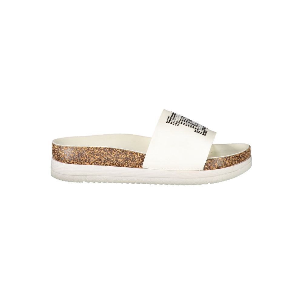 Female model wearing Laura Biagiotti white polyethylene slippers with a wide white upper band adorned with rhinestone crystal embellishment, cork-effect platform midsole, and white rubber outsole, captured mid-step in a casual lifestyle pose showcasing the slipper's glamorous summer style and Italian designer flair.