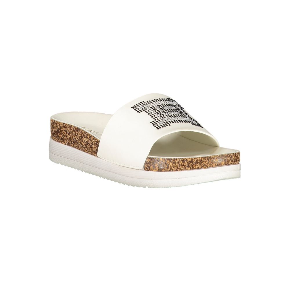 Female model wearing Laura Biagiotti white polyethylene slippers with a wide white upper band adorned with rhinestone crystal embellishment, cork-effect platform midsole, and white rubber outsole, captured mid-step in a casual lifestyle pose showcasing the slipper's glamorous summer style and Italian designer flair.