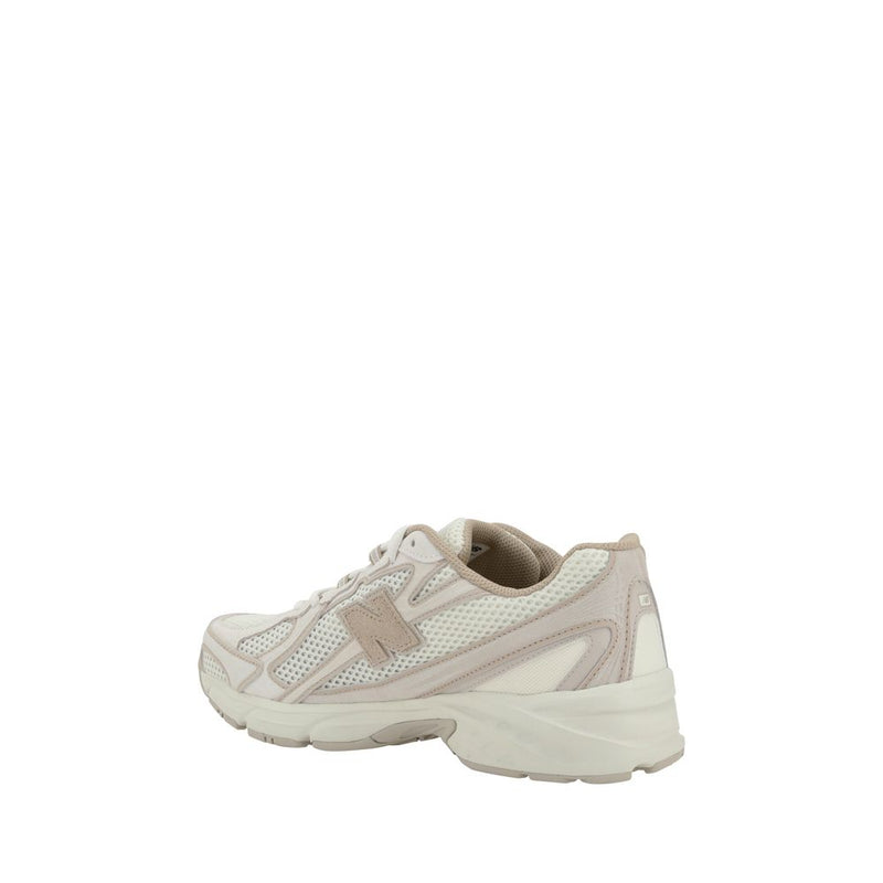 New Balance sneaker in off-white mesh and suede with a chunky cream sole, seen from a rear-side angle.