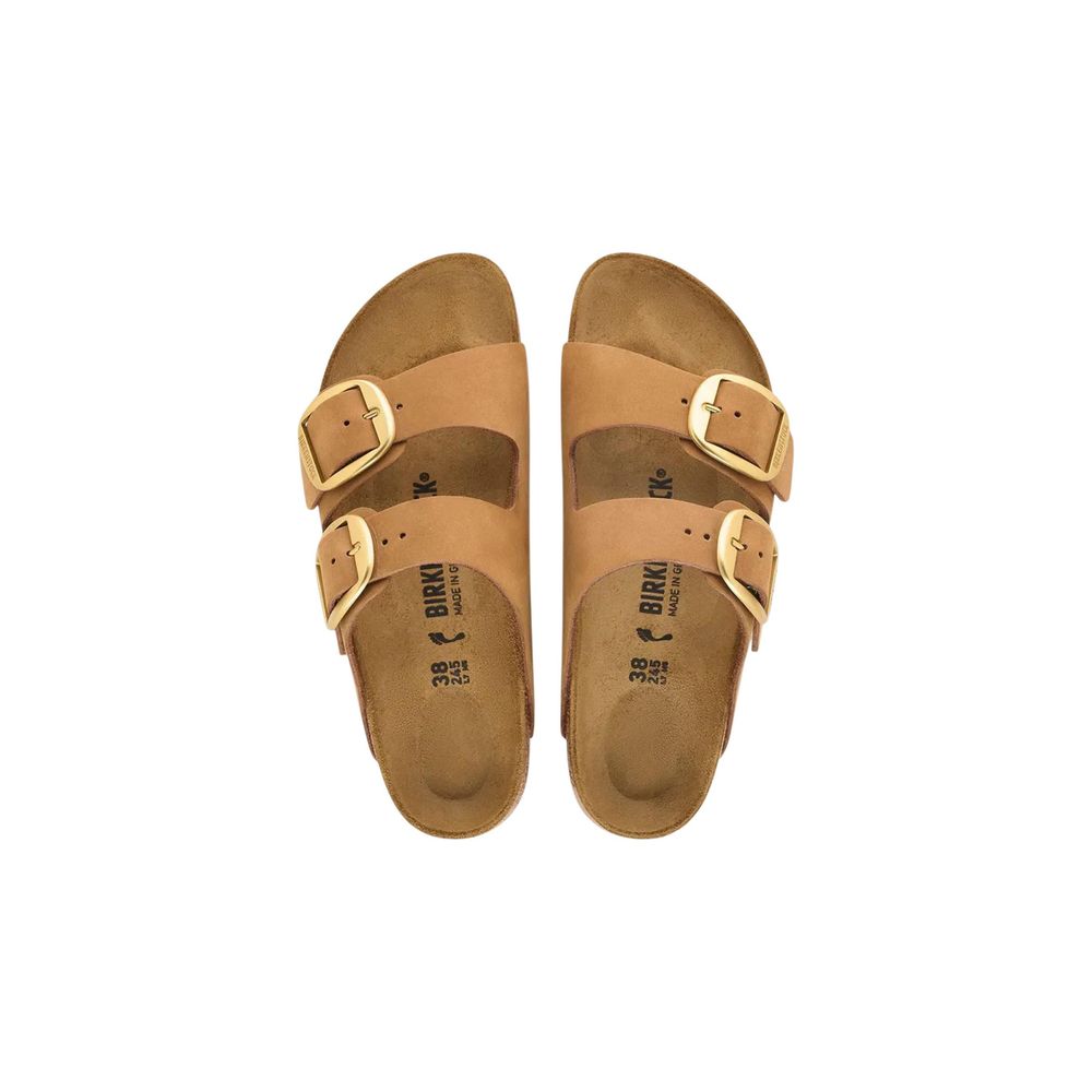 Tan suede Birkenstock Arizona sandals with two wide straps and oversized gold-tone buckles, isolated on white.