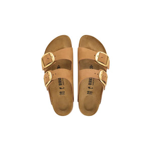 Tan suede Birkenstock Arizona sandals with two wide straps and oversized gold-tone buckles, isolated on white.