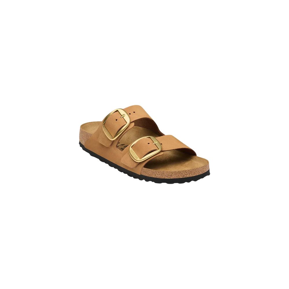 Tan leather slide sandal with a cork footbed and large gold-toned buckles, set against a white background.