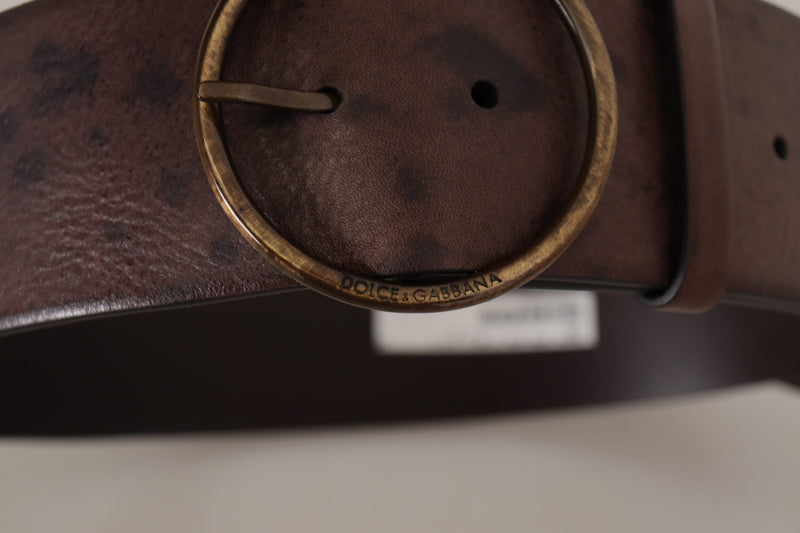 Dark brown leather wide belt with a distressed finish and a large round antique brass buckle featuring embossed logo text