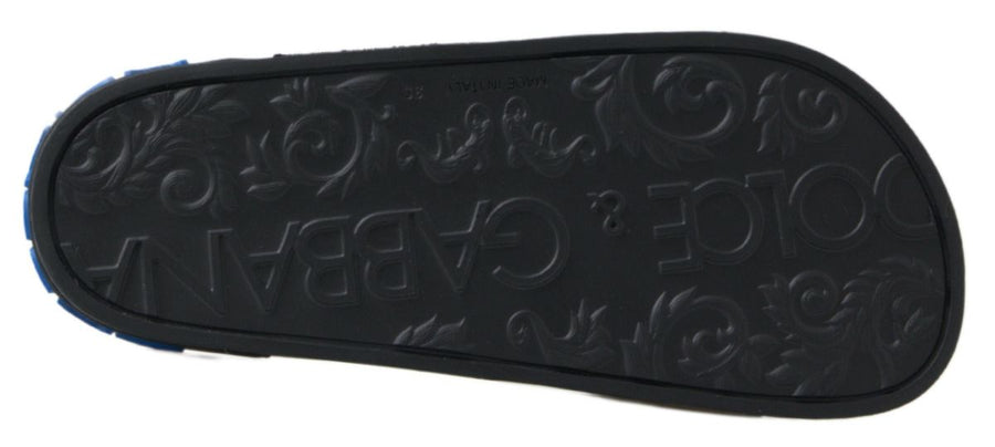 Black rubber slide sandal with blue Dolce & Gabbana logo text on the side and a decorative embellishment on the strap.