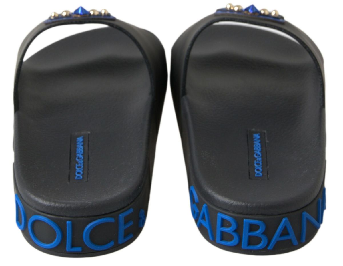 Black rubber slide sandals with blue Dolce & Gabbana logo embossed on side, embellished with blue and gold studs.