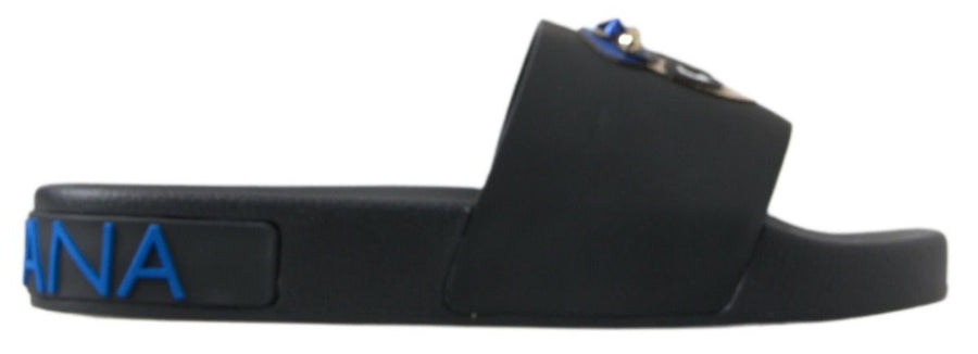 Black rubber slide sandal with blue Dolce & Gabbana logo text on the side and a decorative embellishment on the strap.