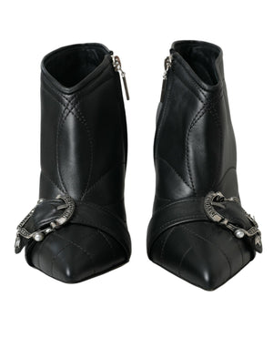 Black quilted leather ankle boots with pointed toes, side zips, and decorative silver Devotion buckled straps.