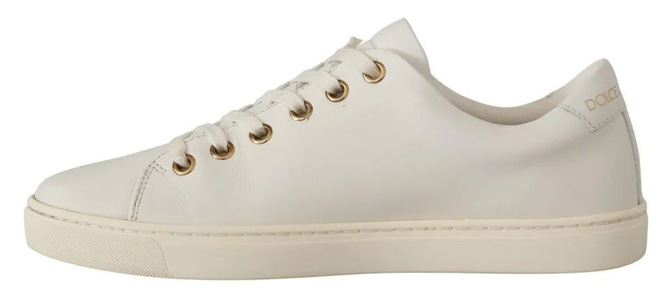 White leather low-top sneaker with gold eyelets and matching laces, featuring subtle branding on the heel tab.