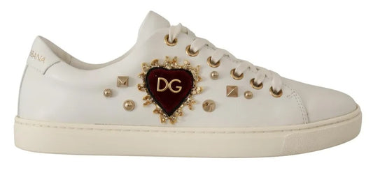 White leather low-top sneaker featuring a red velvet heart emblem, gold DG logo, and decorative gold studs.
