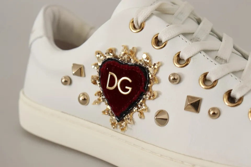 White leather sneaker with gold eyelets, metal studs, and a red velvet heart appliqué featuring a gold DG logo.