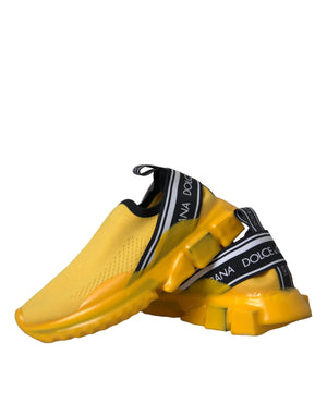 Yellow stretch knit slip-on sneakers with black logo-branded elastic bands and thick, sculpted yellow rubber soles.