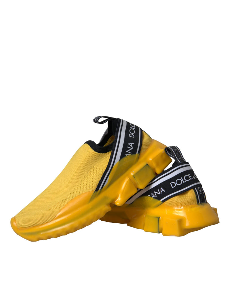 Yellow stretch knit slip-on sneakers with black logo-branded elastic bands and thick, sculpted yellow rubber soles.
