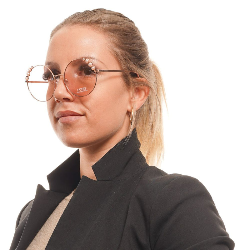 Guess round rose gold metal sunglasses with pearl accents on the oversized frames worn by a woman