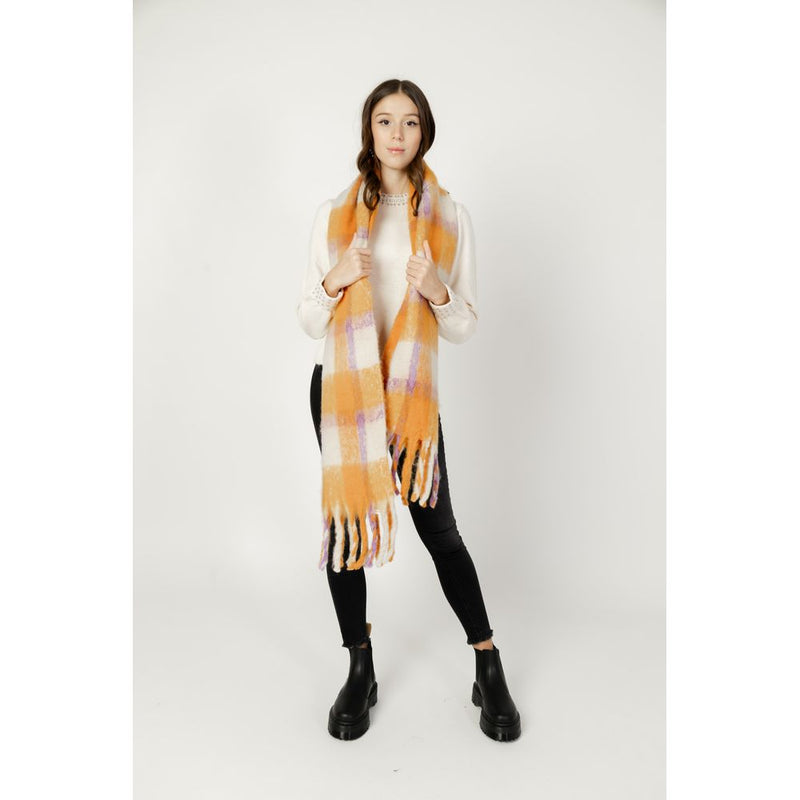 Fuzzy orange plaid polyester scarf with fringe worn over a white sweater