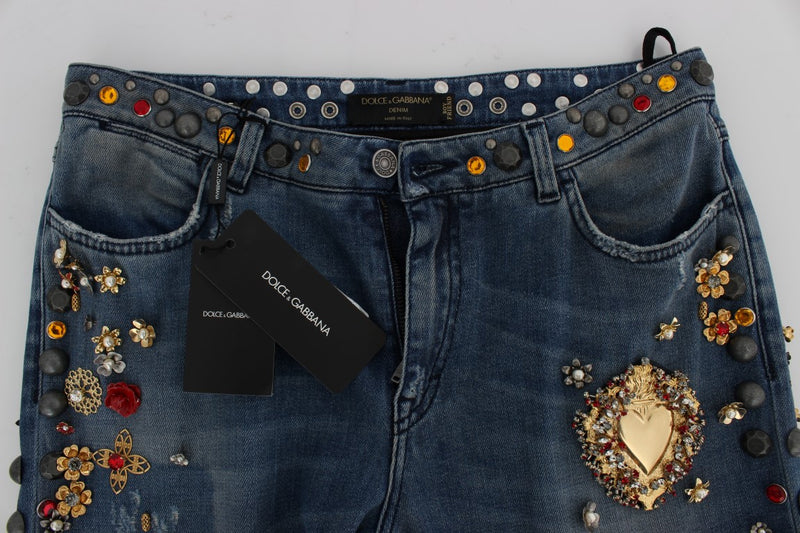 Blue denim jeans embellished with colorful crystal flowers and a large gold heart emblem