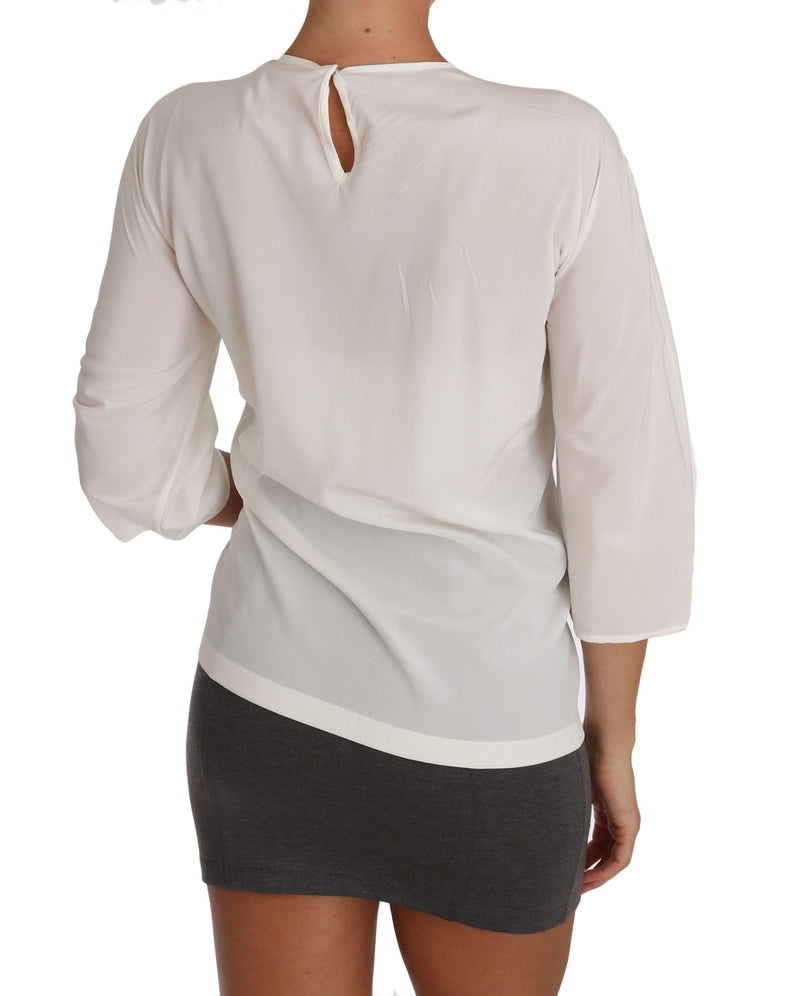 White silk blouse with long sleeves and back keyhole closure worn over a dark skirt