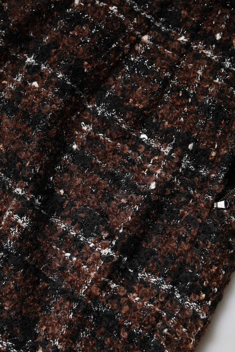 Close-up of a brown, black, and white tartan tweed pencil skirt with textured fabric