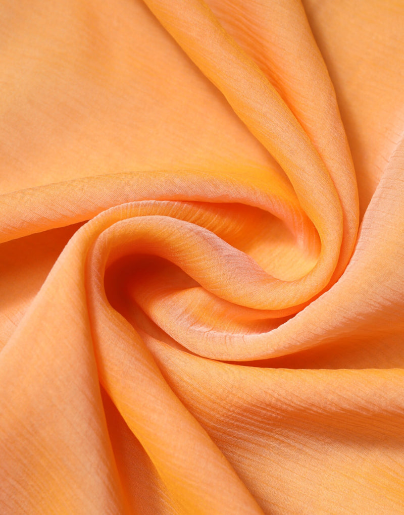 Close-up of bright orange silk wrap scarf with soft, flowing folds