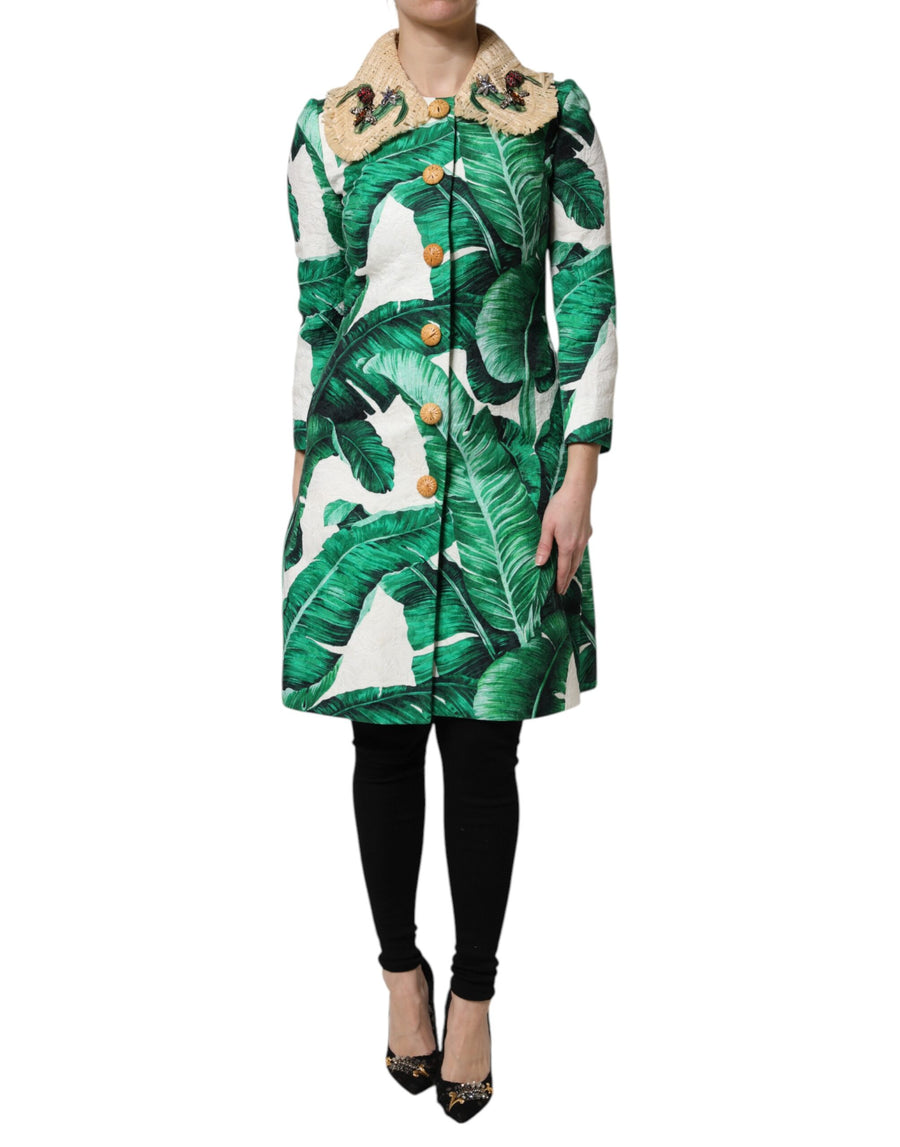 Green and white banana leaf print trenchcoat with straw collar and jewel buttons worn by a model