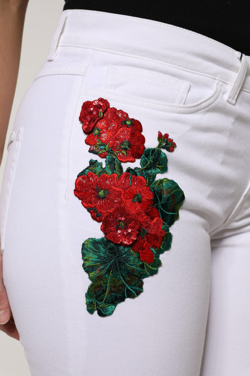 White denim jeans featuring red sequined floral embroidery with green leaves