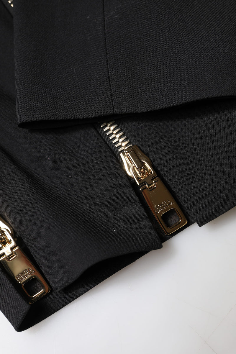 Close-up of black wool pants with gold zippers at the cuffs