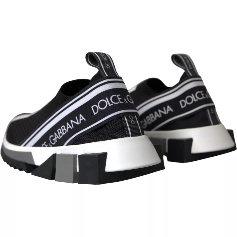 Black and white knit slip-on sneakers with logo tape, structural rubber sole, and jagged traction tread.