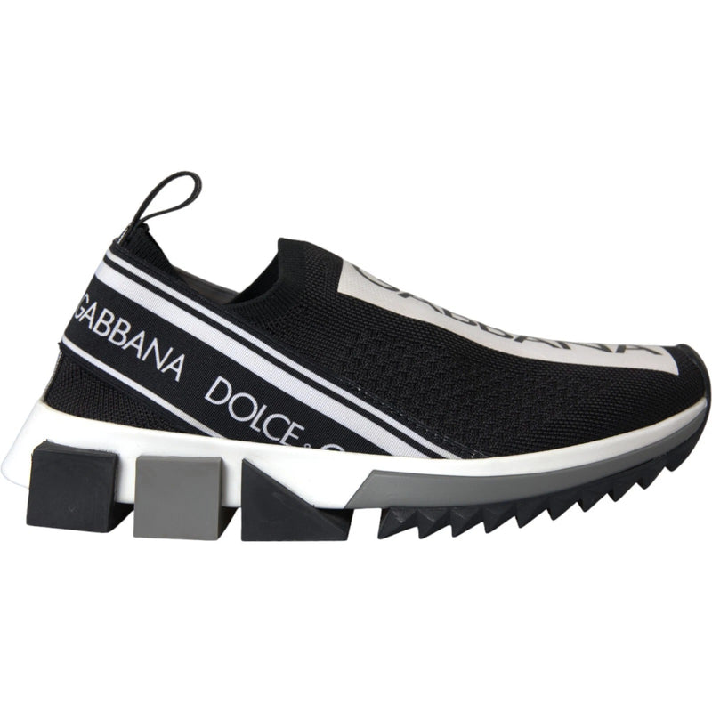 Black and white knit slip-on sneakers with logo tape, structural rubber sole, and jagged traction tread.