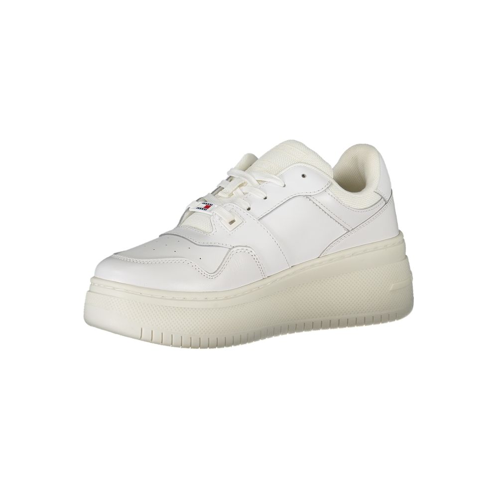 Female model wearing Tommy Hilfiger bianco white leather women's sneakers with a clean white leather upper, classic Tommy Hilfiger flag branding, and sporty white sole, captured mid-step in a casual lifestyle pose showcasing the sneaker's timeless preppy style and everyday versatility.