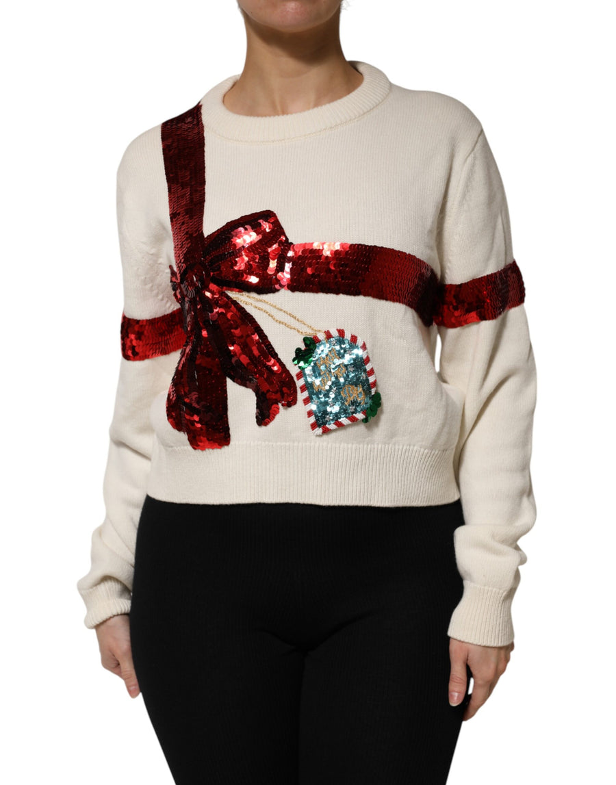 White crew neck sweater with a red sequined gift bow and tag