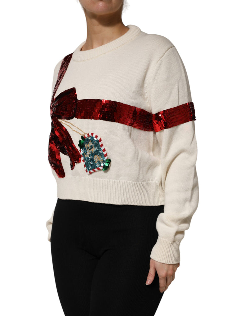 White knit crew neck sweater with a large red sequined gift bow and tag graphic
