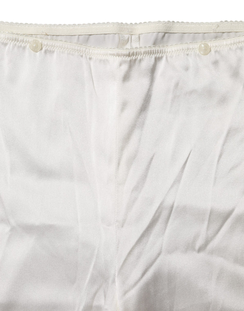 Close-up of ivory silk tapered high-waist pants with button details