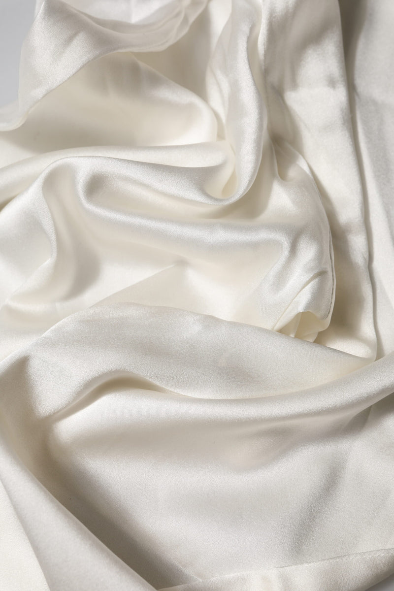 Close-up of smooth, shiny ivory silk fabric draped softly