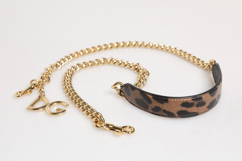 Gold curb chain shoulder strap with brown leopard print leather pad and DG charm on white background