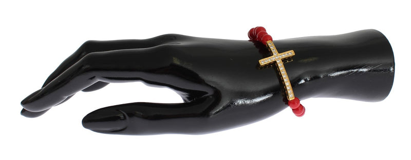 Red coral bead bracelet featuring a gold cross pendant with clear cubic zirconia crystals on a black mannequin hand