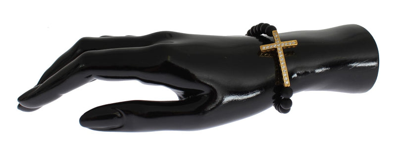 Matte black onyx beaded bracelet with a gold cubic zirconia cross charm on a black hand form