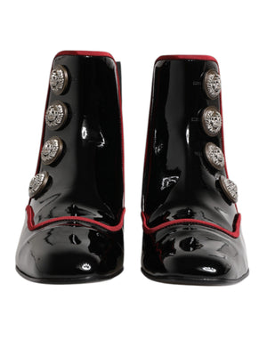 Dolce & Gabbana black patent leather ankle boots with red piping and decorative silver military-style buttons.