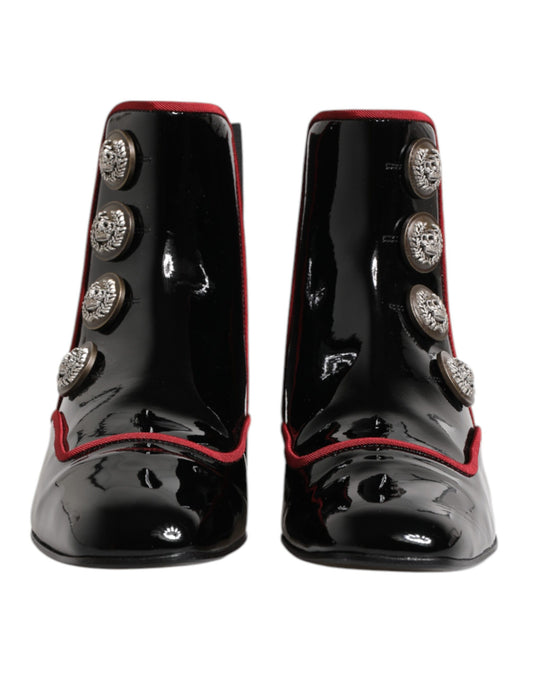 Dolce & Gabbana black patent leather ankle boots with red piping and decorative silver military-style buttons.
