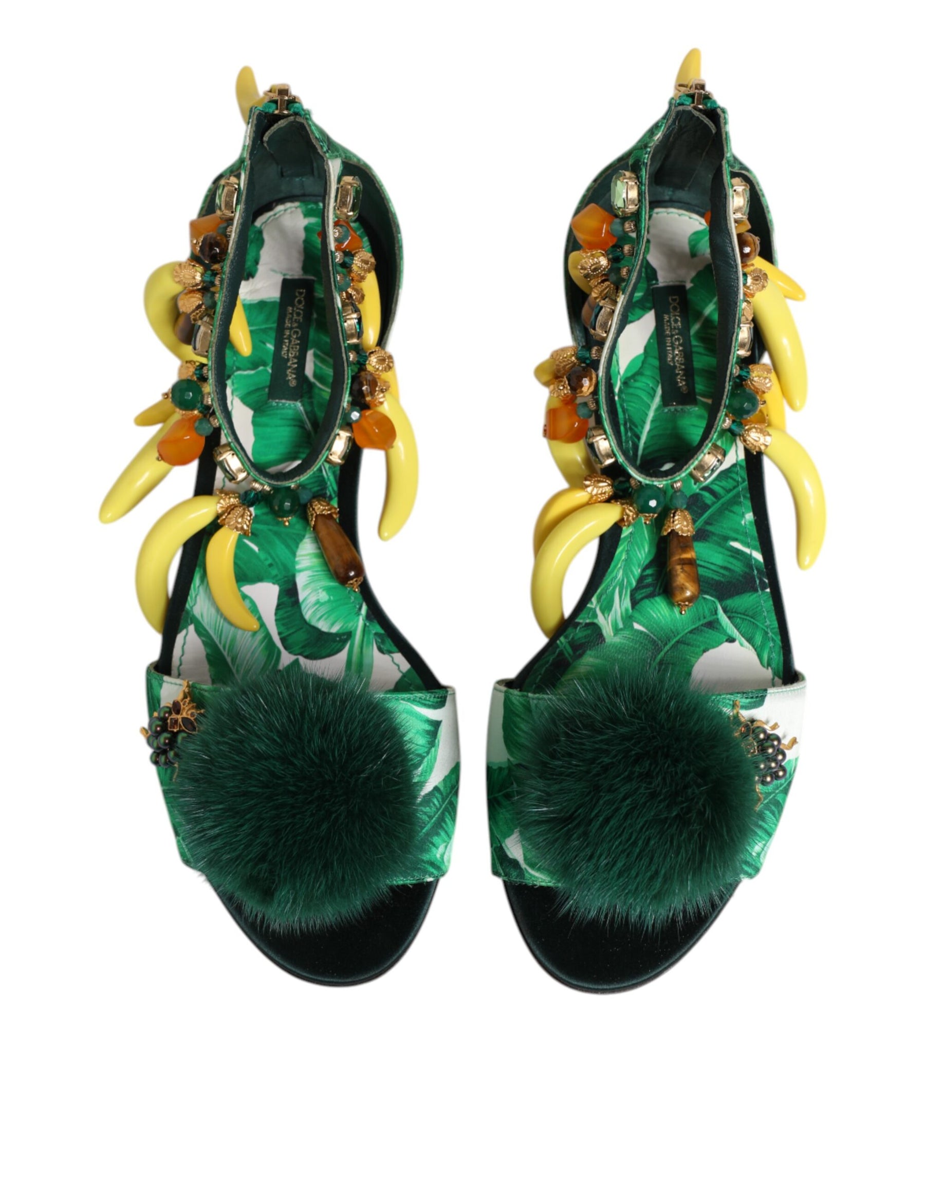 Green high-heeled shoes with decorative elements on a white background