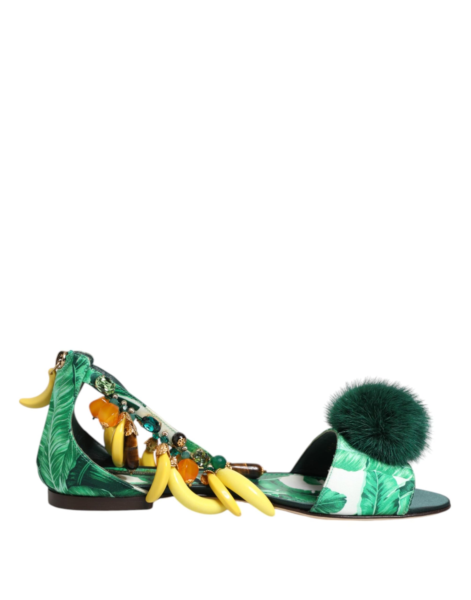 Green sandals with banana and pom-pom details on a white background