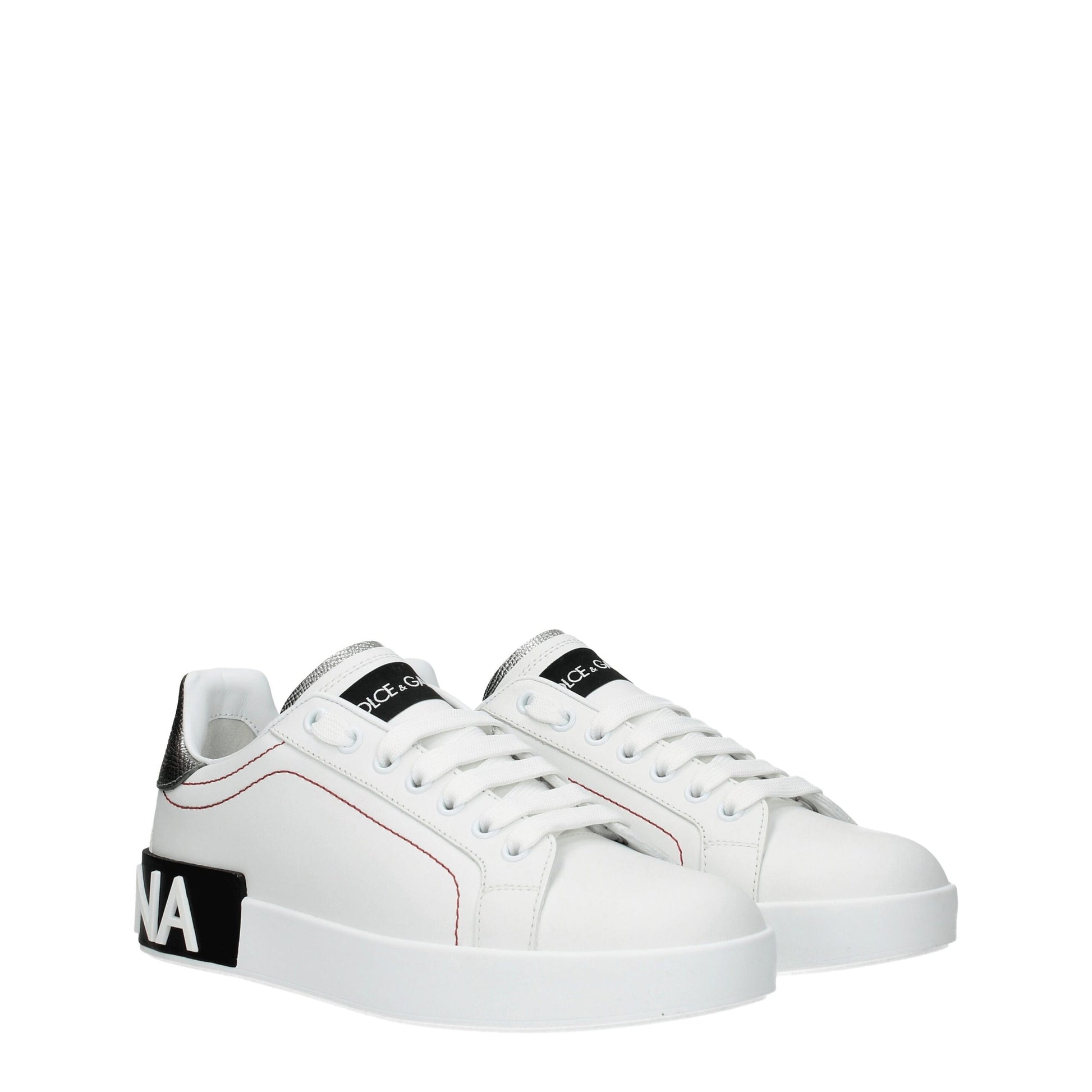 Female model wearing Dolce & Gabbana white leather low top sneakers with a clean white leather upper, signature branded detailing, and sleek low-profile sole, captured mid-step in a casual lifestyle pose showcasing the shoe's refined silhouette and luxury craftsmanship.