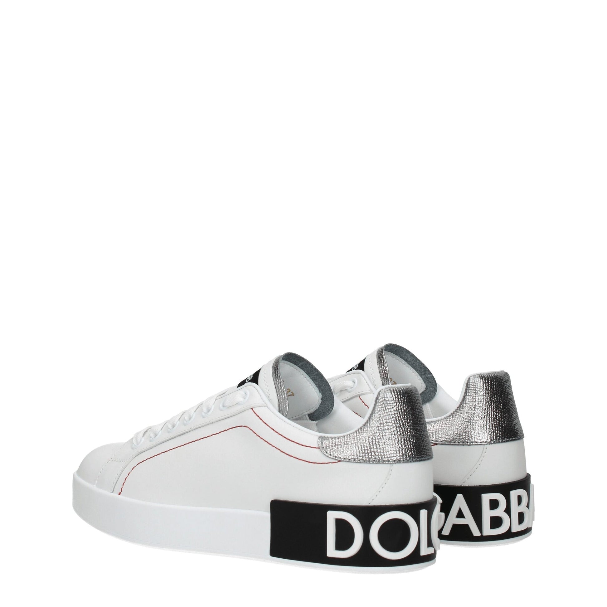 Female model wearing Dolce & Gabbana white leather low top sneakers with a clean white leather upper, signature branded detailing, and sleek low-profile sole, captured mid-step in a casual lifestyle pose showcasing the shoe's refined silhouette and luxury craftsmanship.