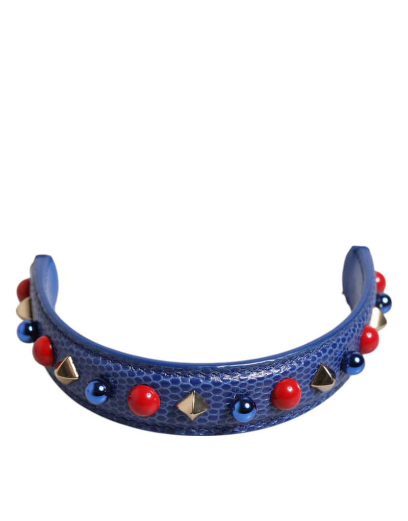 Blue textured leather bag handle adorned with red spheres, blue beads, and gold studs