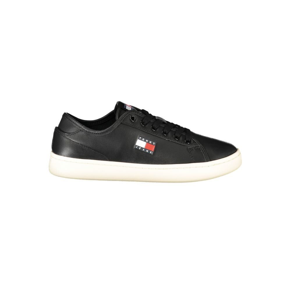 Tommy Hilfiger women's black polyurethane sneaker with lace-up closure, white sole, and side logo patch.