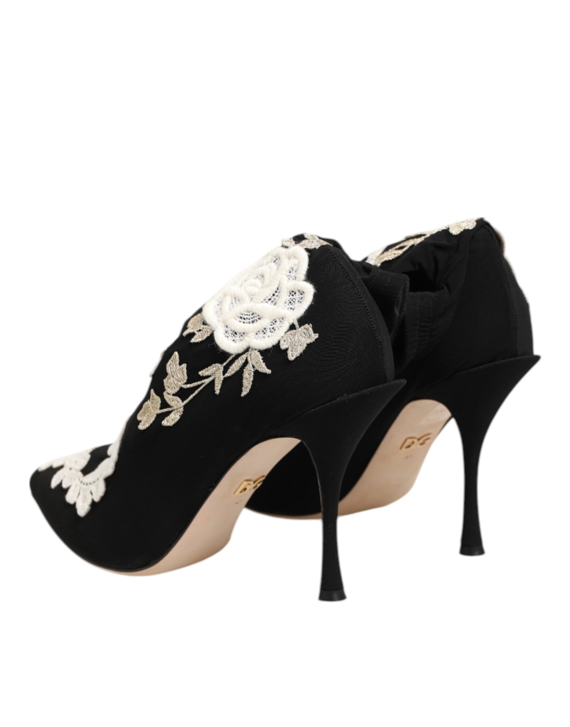 Black satin stiletto pumps featuring intricate white lace floral embroidery on the heel and toe.
